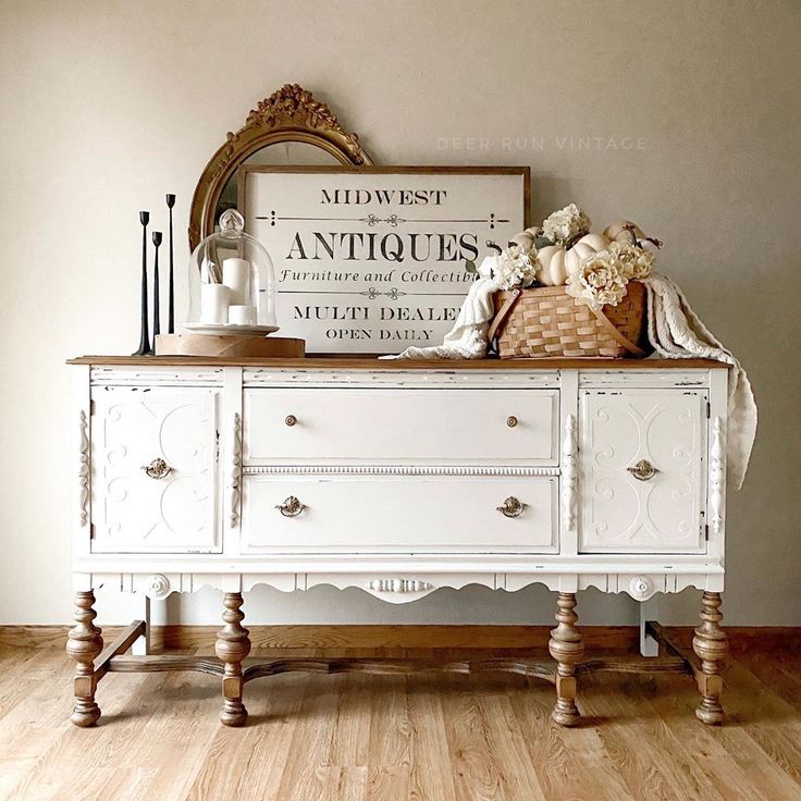 a white dresser with an antique sign above it