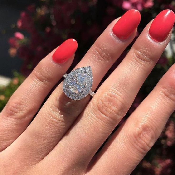 a woman's hand with red nail polish and a diamond ring on her finger