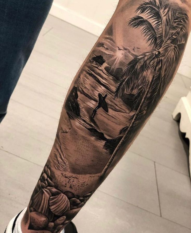 a man's arm with a beach scene and palm trees on it, in black and white