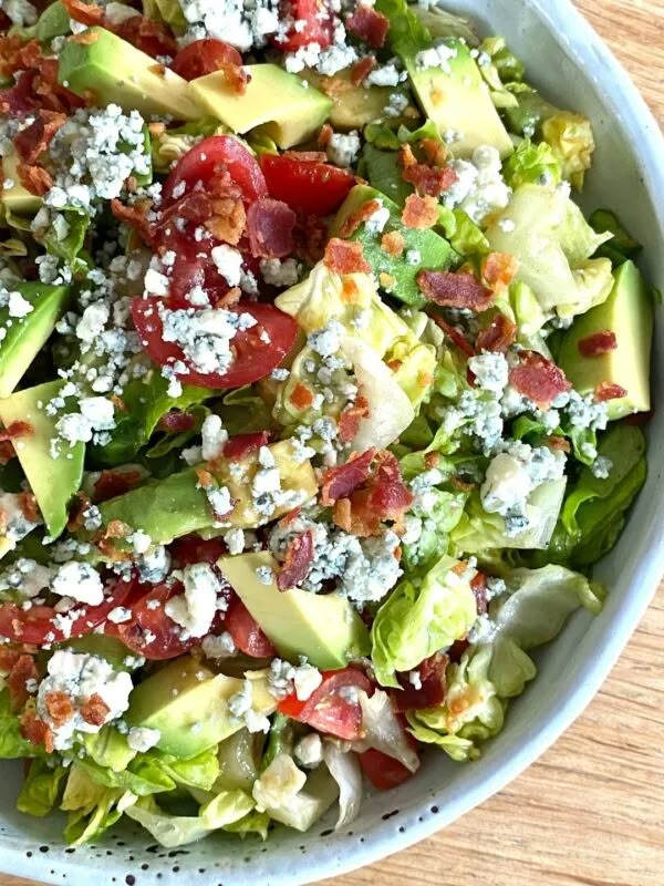 a salad with lettuce, tomatoes, avocado and feta cheese