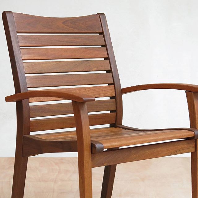 a wooden chair with slatted back and arm rests on a hard wood floor