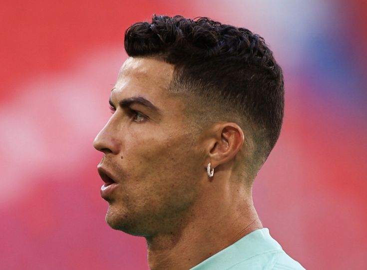 a close up of a person with a soccer ball in the background and a red wall behind him