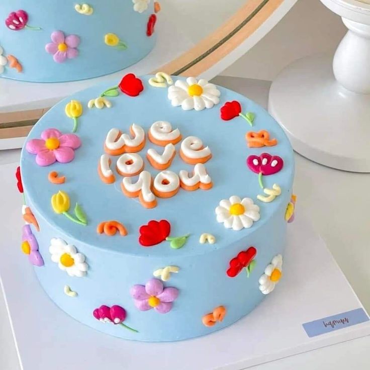 a blue cake decorated with flowers and the word love spelled in frosting on top