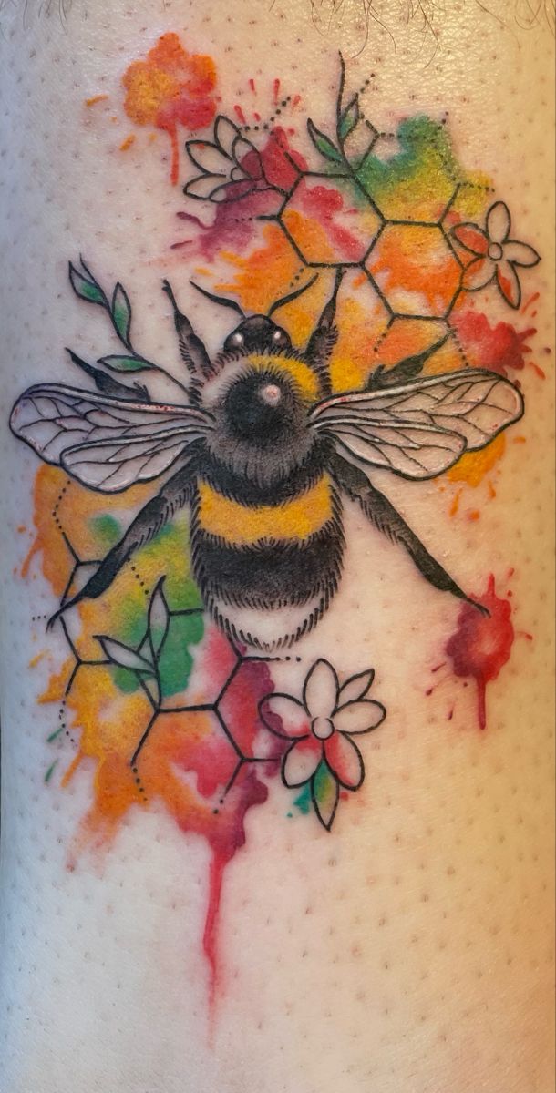 a tattoo with a bee and flowers on the back of its leg, painted in watercolors