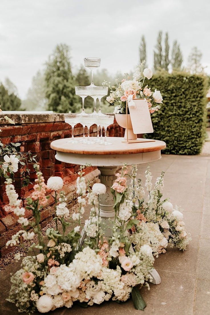 a cake on top of a table surrounded by flowers and greenery in front of a brick wall