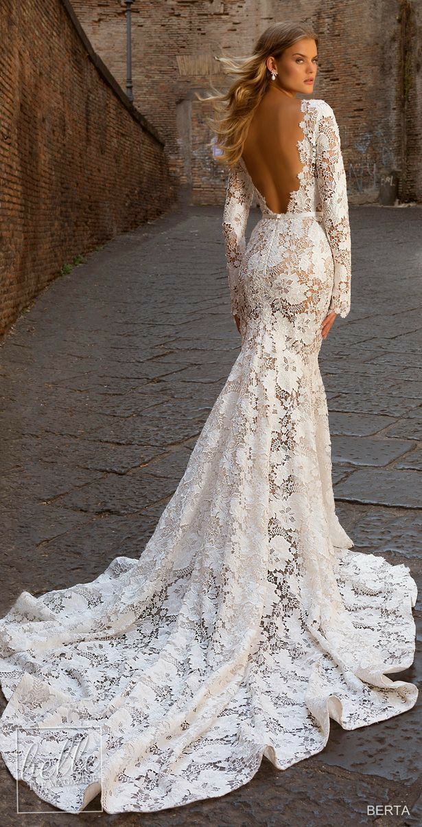 a woman in a white wedding dress standing on a cobblestone street with her back to the camera