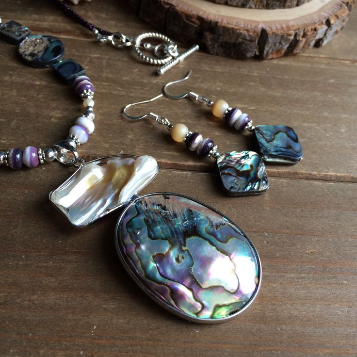 Abalone necklace set shell pendant necklace puka shell boho necklace tribal beach necklace ocean puka surf gift set unique jewelry for women This beauty has a 70mm natural abalone free form pendant, inlaid and wrapped with mother of pearl on one side, 10mm-14mm amethyst gemstone beads, 6mm mother of pearl gemstone, 5mm rare purple lip oyster puka shell beads, 13 0 iris purple seed beads, 12mm silver bali shell beads, silver findings and toggle clasp. Length is 20 inches approx. Earrings: approx Shell-shaped Mother Of Pearl For Jewelry Making, Bohemian Mother Of Pearl Shell Gift, Handmade Shell-shaped Mother Of Pearl Jewelry, Artisan Shell Jewelry For Gifts, Artisan Shell Jewelry Gift, Handmade Shell Dangle Jewelry, Unique Abalone Shell Jewelry For Beach, Bohemian Shell Jewelry As A Gift, Bohemian Shell Jewelry Gift