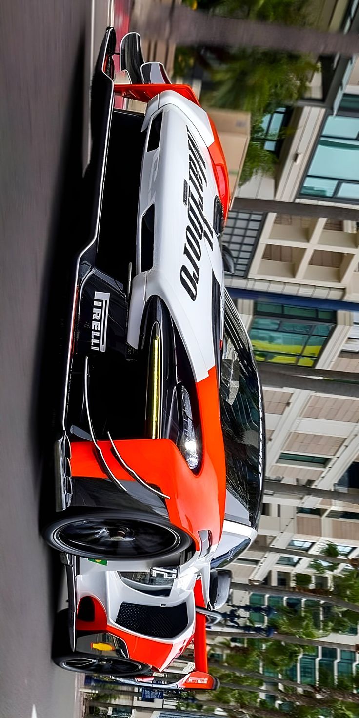 an orange, white and black car hanging from the side of a building