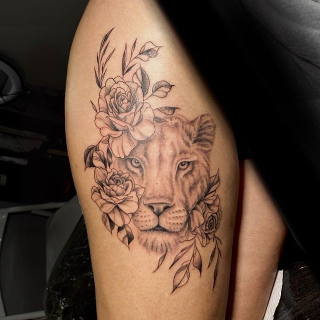 a woman's thigh with a lion and roses tattoo on it