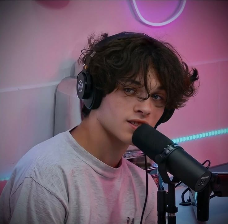 a young man wearing headphones sitting in front of a microphone