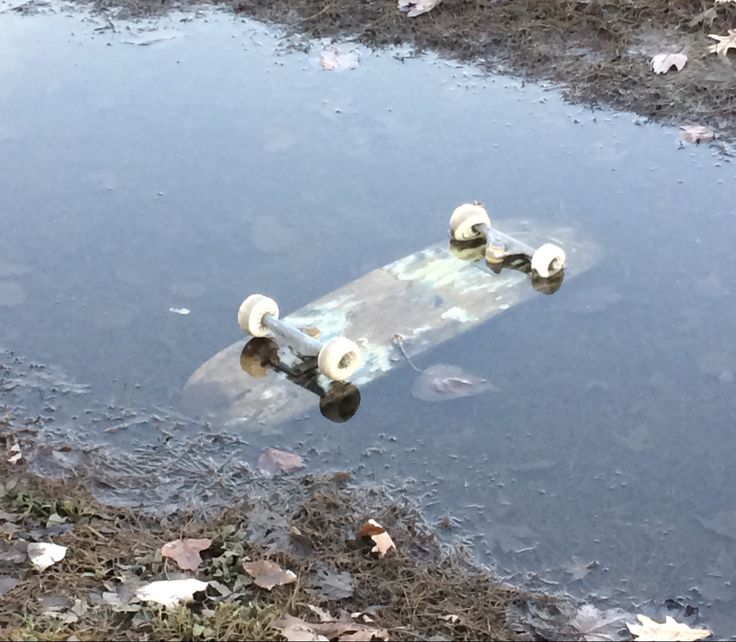 an old skateboard sitting in the middle of some water