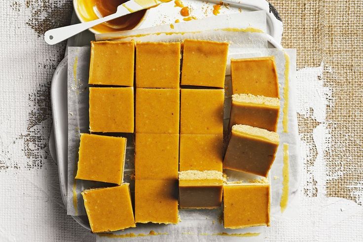 several squares of peanut butter fudge on a plate next to a spoon and bowl