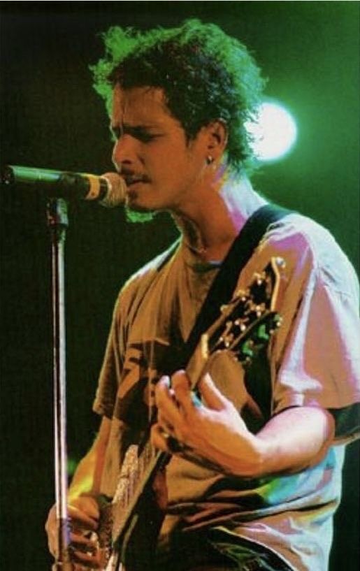 a man with green hair playing guitar on stage