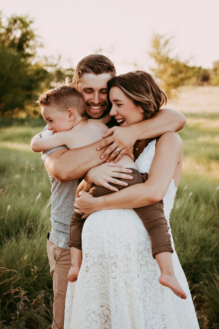 a man and woman are hugging each other while holding a small child in their arms