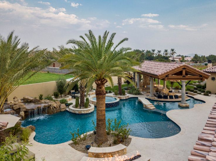 an outdoor swimming pool surrounded by palm trees