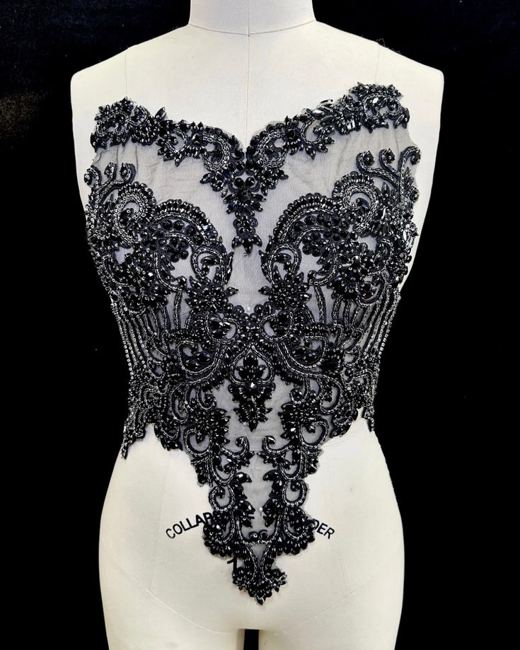 a white mannequin with black beading on it's chest and back