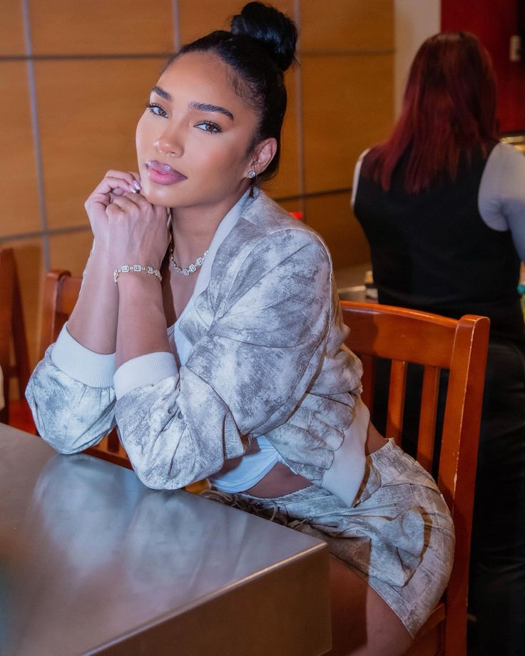 a woman sitting at a table with her hand on her chin and looking off to the side