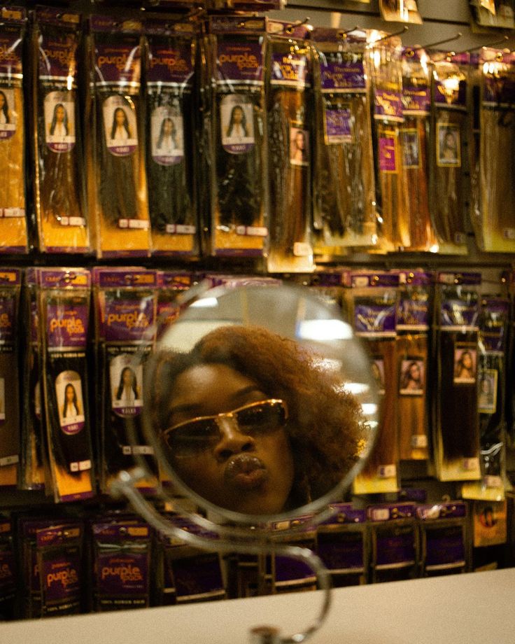 a woman's face is reflected in a round mirror on a table with gold packages behind her