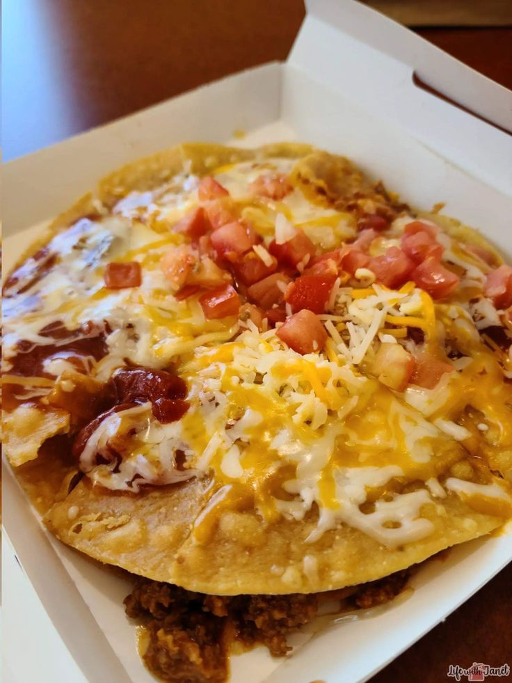 a close up of a taco in a box with toppings on the side