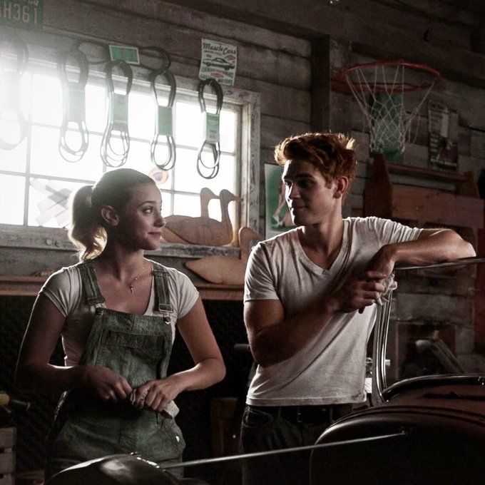 a young man and woman standing next to each other in a garage with tools hanging on the wall