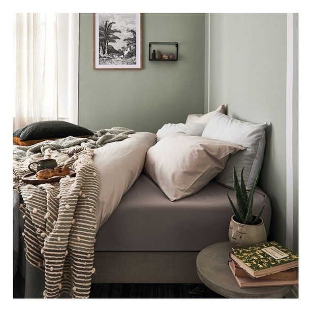 a bed with pillows and blankets on top of it next to a window in a bedroom