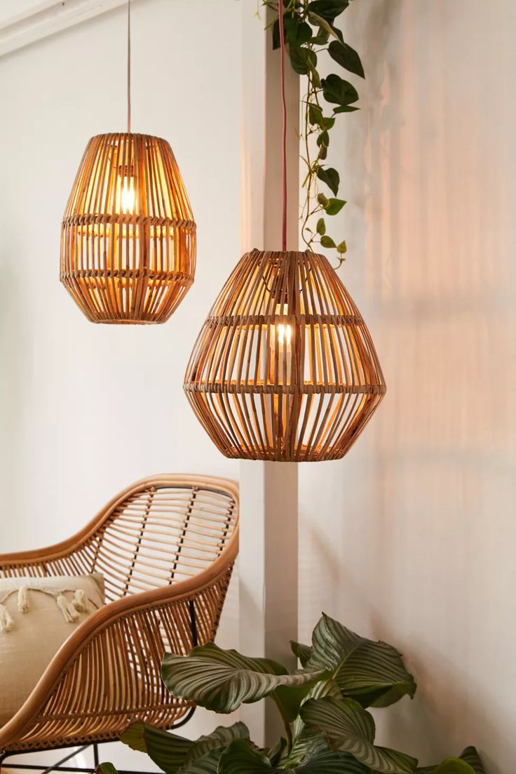 two wicker lamps hanging from the ceiling next to a chair and potted plant