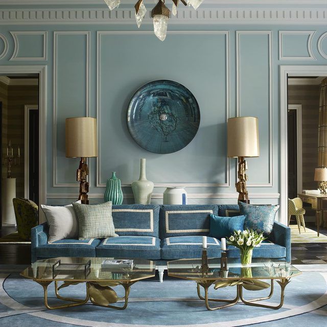 a living room with blue couches and white walls in front of a circular mirror