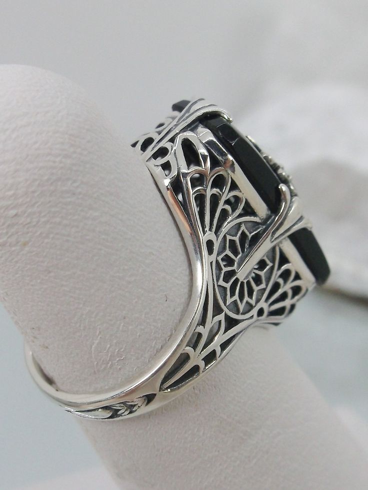 Black Camphor Glass Solid Sterling Silver Ring Grace Design#D233 This is a lovely antique Edwardian era inspired filigree ring. This gorgeous ring is created in stunning black camphor glass. The glass is embellished with a delicate floral filigree. The top of the ring holds a center set 1mm round cut gemstone (Choose from white Cubic Zirconia, lab created white Moissanite, or Natural/Genuine White Diamond). The black glass is 18mm x 19mm. The ring sits 18mm north-south and 10mm east-west on the Black Filigree Ring With Intricate Design For Formal Occasions, Classic Black Filigree Ring For Formal Occasions, Black Filigree Ring For Formal Occasions, Elegant Black Filigree Ring For Anniversary, Formal Black Filigree Ring, Antique Black Filigree Ring For Formal Occasions, Black Filigree Ring With Intricate Design, Elegant Black Filigree Ring Gift, Classic Black Filigree Wedding Ring