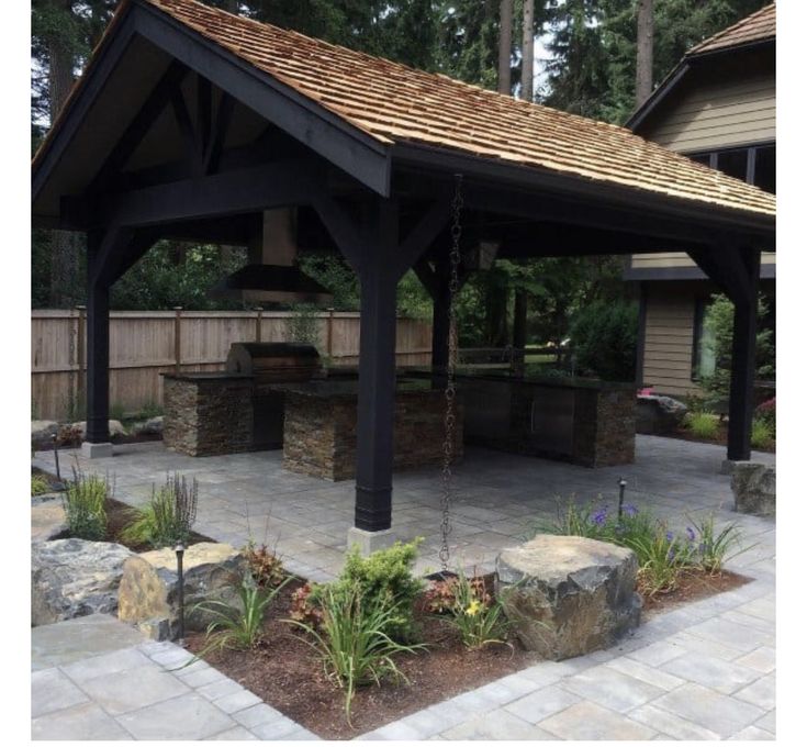 a gazebo in the middle of a yard with rocks and plants