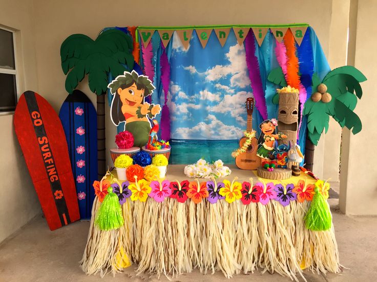 the table is decorated with flowers, grass and hula skirtes for hawaiian luau party