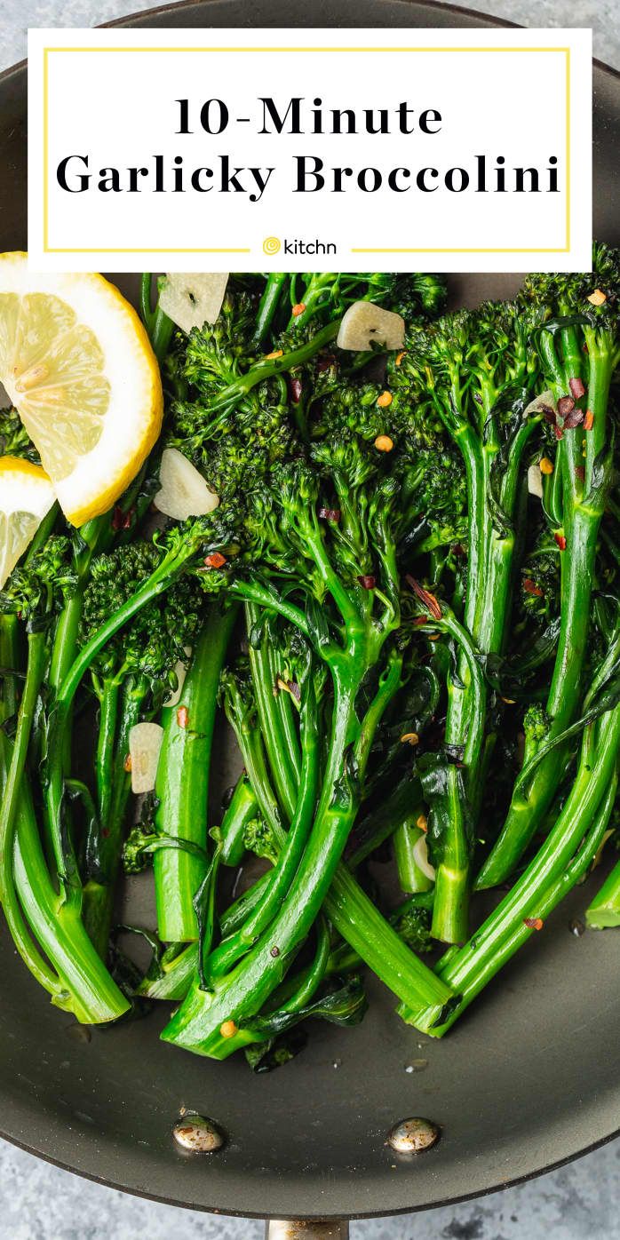 broccoli is being cooked in a pan with lemon wedges on the side