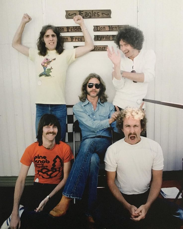 four people sitting on a chair with their arms in the air and one person standing up