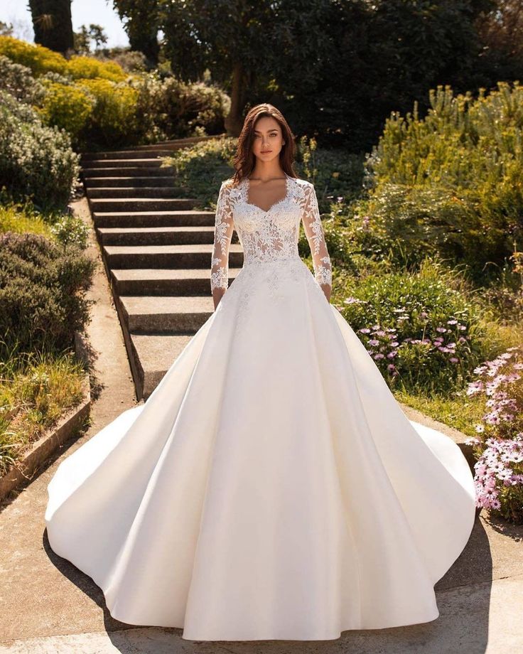 a woman in a white wedding dress standing on some steps