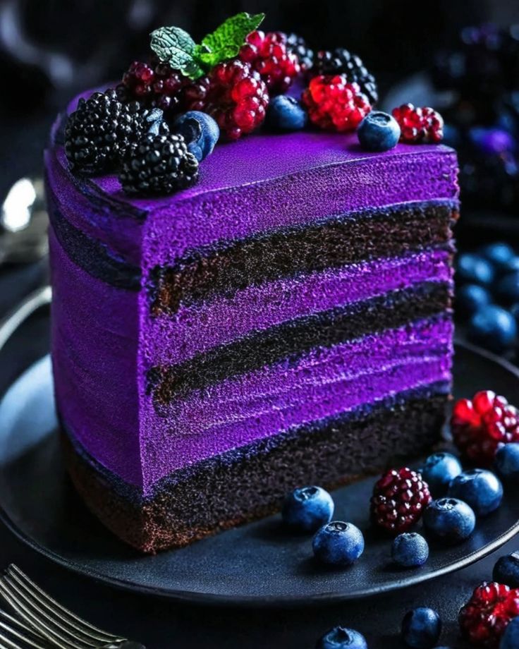 a slice of purple cake with berries and blueberries on the top is ready to be eaten