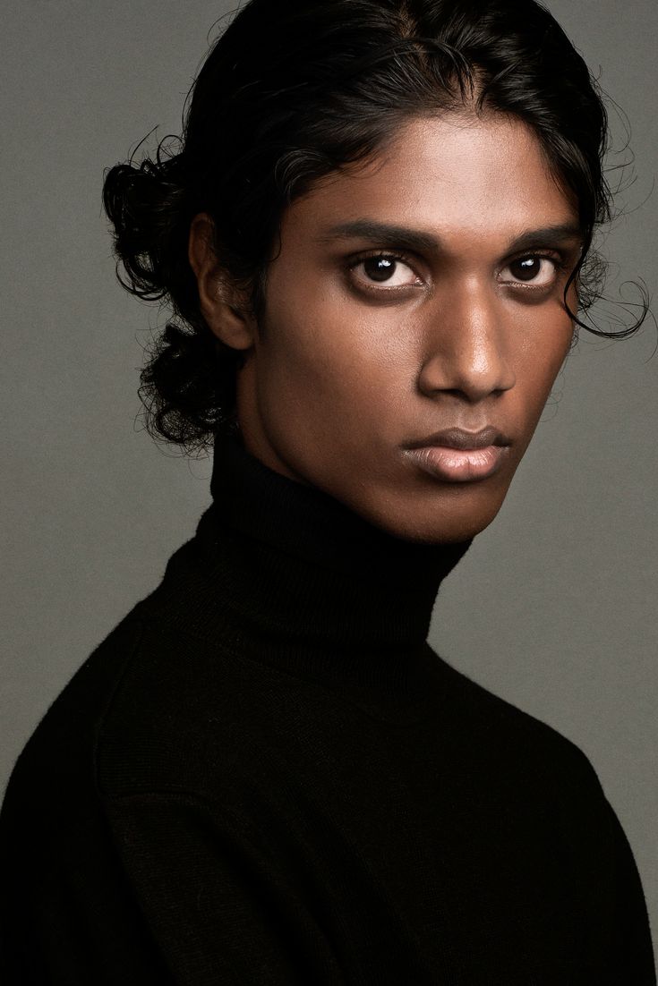 a woman with dark hair wearing a black turtle neck sweater and looking at the camera