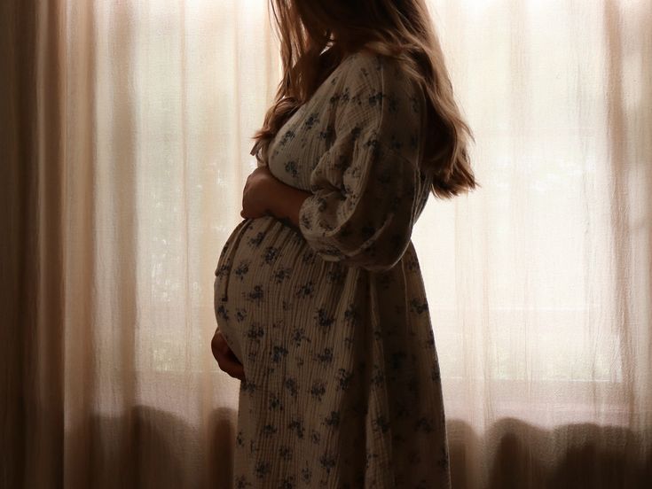 a pregnant woman standing in front of a window