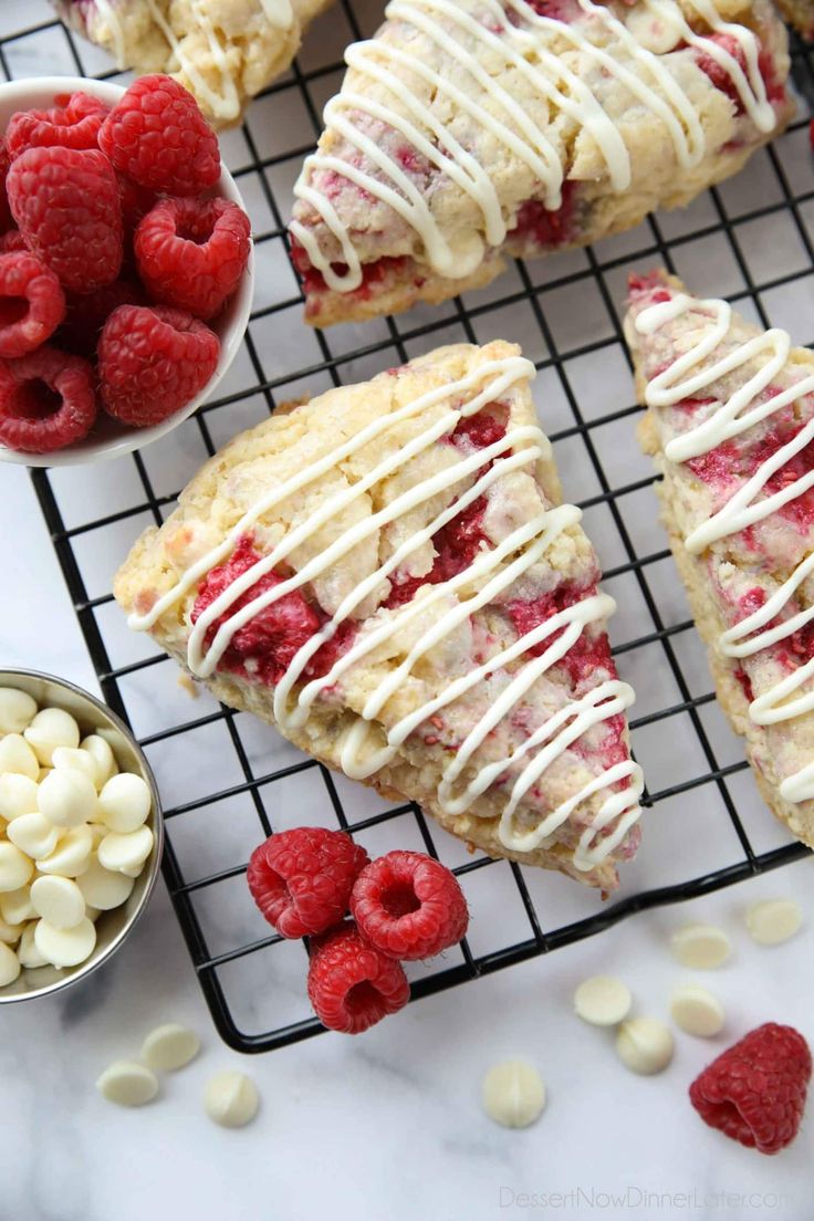 raspberry scones with white chocolate drizzled on top and fresh raspberries