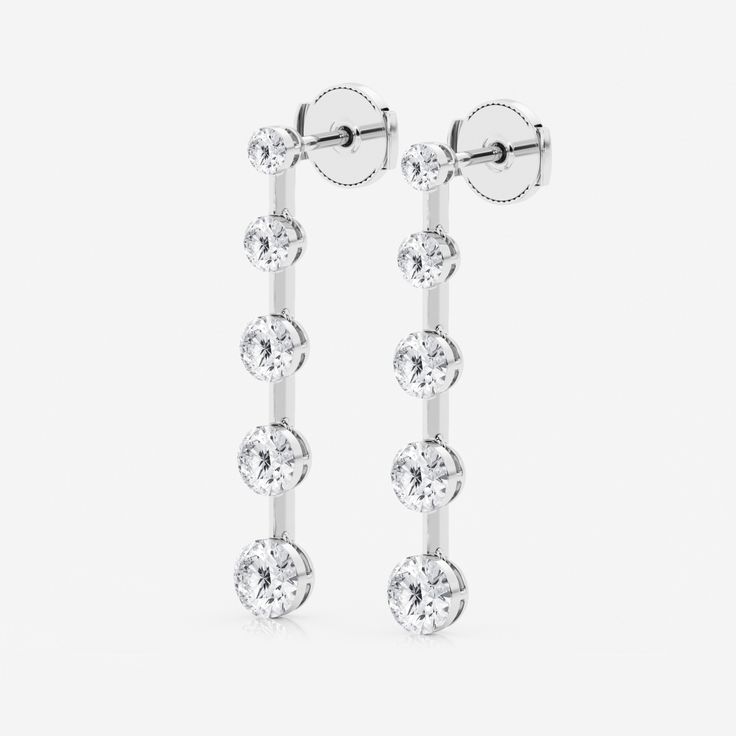 two pairs of earrings with cubicles on each ear, one in white gold and the other in silver