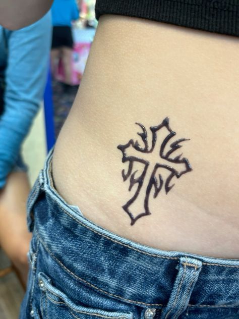 a cross tattoo on the side of a woman's stomach