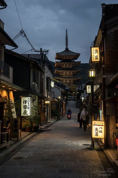 an alley way with people walking down it at night time and lanterns hanging from the ceiling