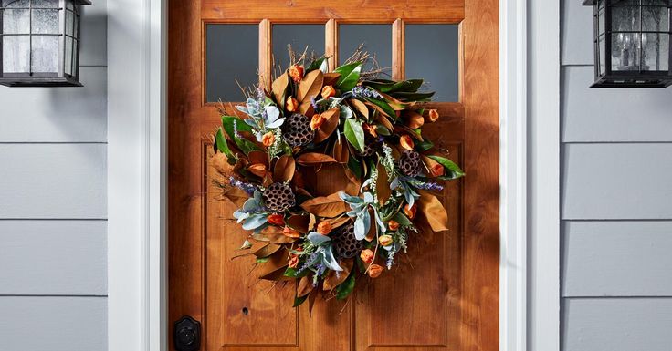 a wooden door with a wreath hanging on it's side and two lights above the door