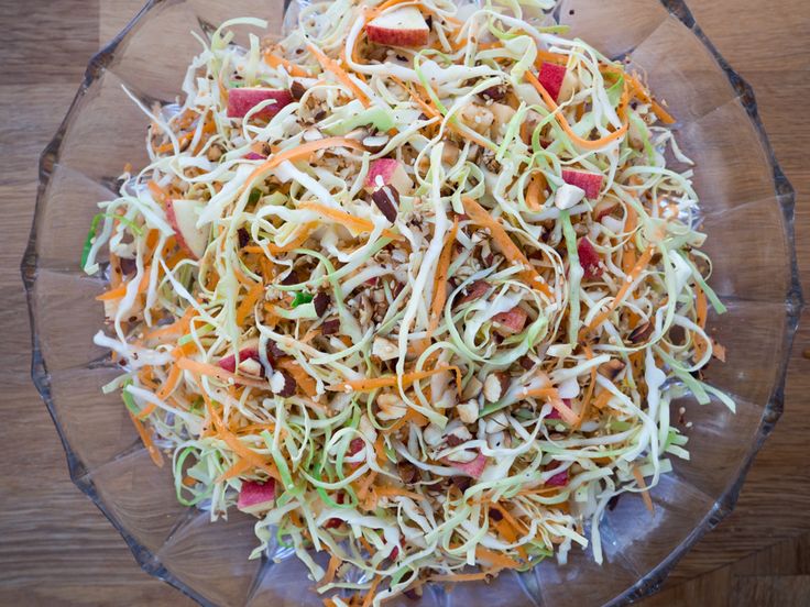 a glass bowl filled with coleslaw slaw and carrots on top of a wooden table