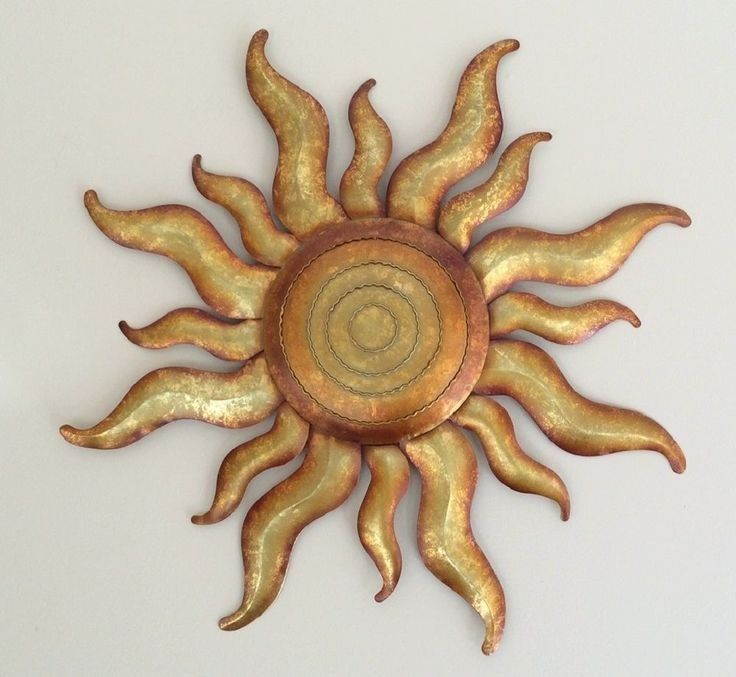 a gold metal sun wall hanging on a white wall