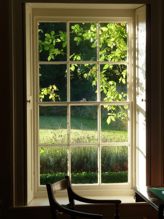 an open window with the sun shining through it and some trees in the back ground