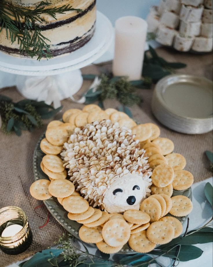 a hedgehog made out of crackers sits on a table next to a cake