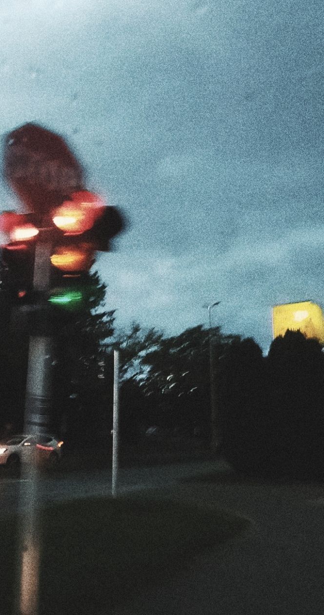 blurry photograph of traffic lights at night with cloudy sky in the backgroud