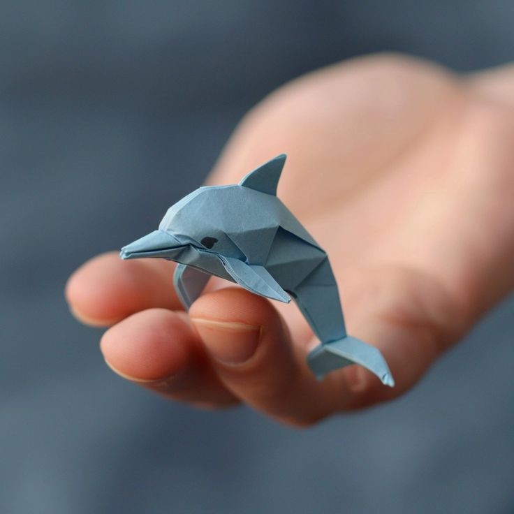 a small origami dolphin in the palm of someone's hand