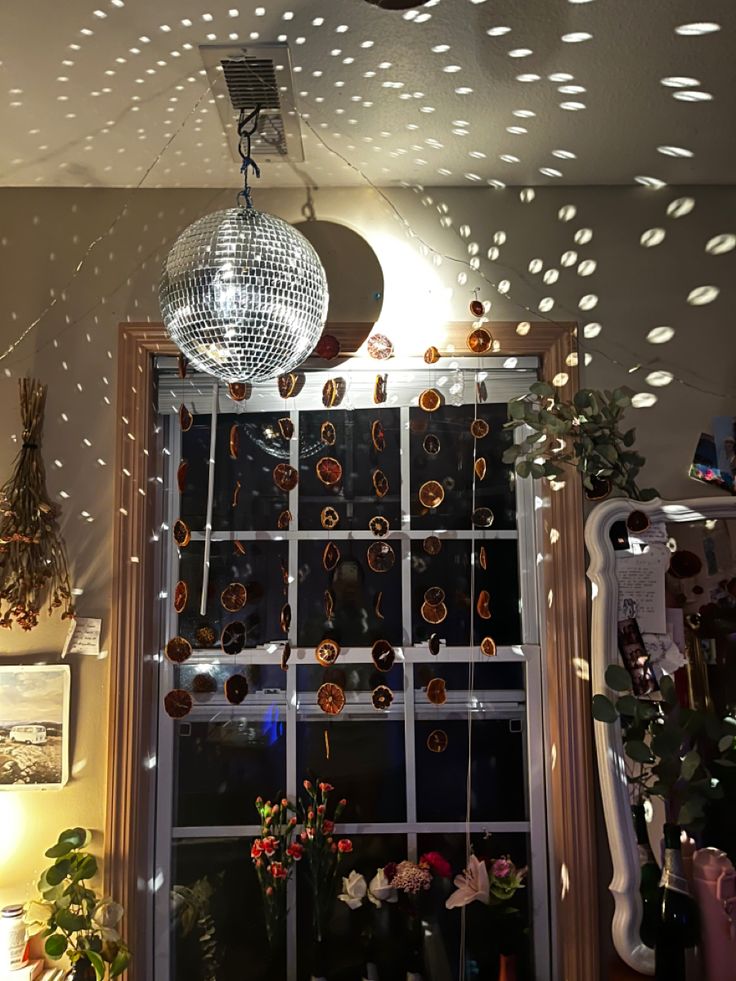 a disco ball hanging from the ceiling in front of a window with lights on it