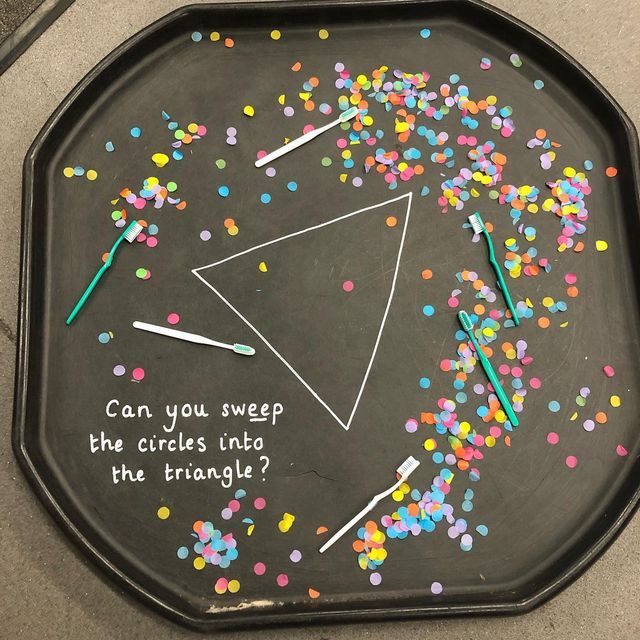 a black tray with confetti on it that says can you sweep the circles into the triangle?