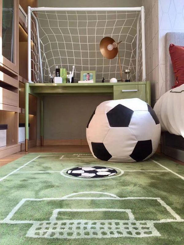 a soccer ball sitting on top of a green rug in front of a bed and desk